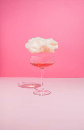 Romantic feelings composition with wine glass and cloud on pastel pink background. Alone for Valentine's Day concept.の写真素材