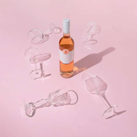 Elegant rose wine bottle and glasses on pastel pink background. Modern Valentine's Day date concept.の写真素材