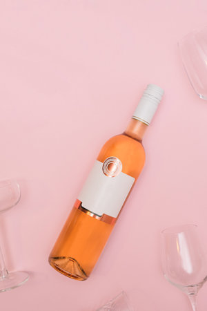 Elegant rose wine bottle and glasses on pastel pink background. Modern Valentine's Day date concept with copy space.の写真素材
