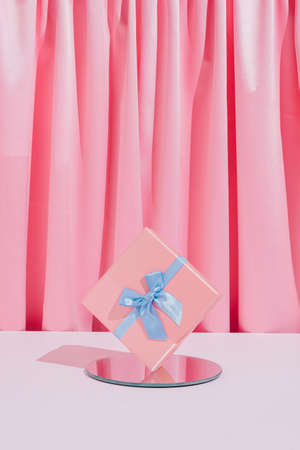 Romantic pastel pink composition with birthday or Valentine's Day gift box with mirror and satin background. Modern minimal concept.の写真素材