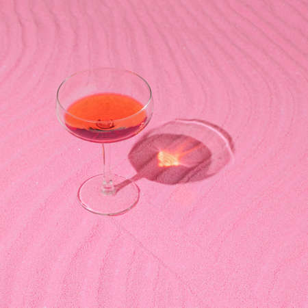 Valentine's Day or birthday party concept with wine glass and pink sand. Minimal and modern girly aesthetic.の写真素材