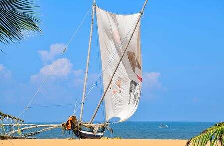 Traditional outrigger fishing boat sailing off the Negombo coastline in Sri Lanka.