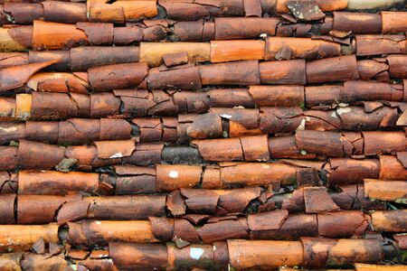 Rustic and broken clay roof tiles on a house