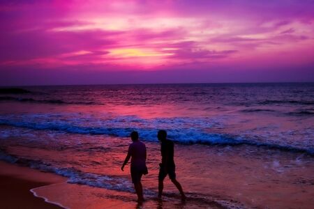 Two friends walking through in the beach during a sunset in sri lankaの写真素材