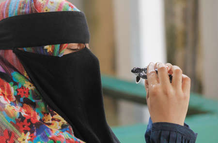 A muslim women wearing niqab is happy with her baby tortoise petの写真素材