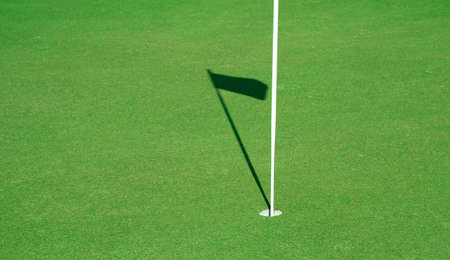Golf course with the shadow of the flagの写真素材