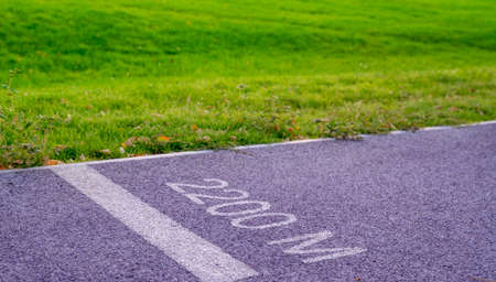 Jogging track in the park at summer day. 2000 meters distance sign painted on asphalt pavement....