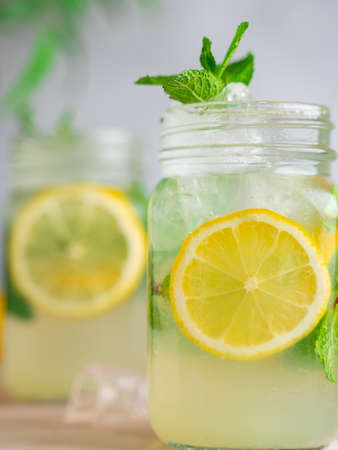 three Lemon mojito cocktail with mint in mason jars on top of wood.