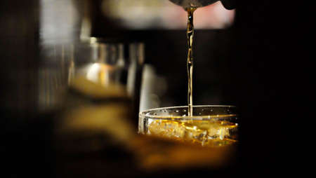 Pour golden liquid into glassの写真素材