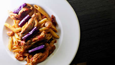 An eggplant pasta dish on a white dinner plateの写真素材
