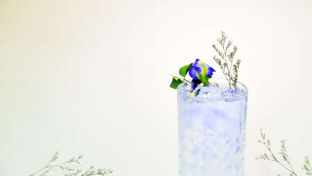 A glass of purple drink in front of a white curtainの写真素材