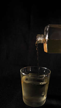 The moment the brown liquid in the glass bottle is poured into the glassの写真素材