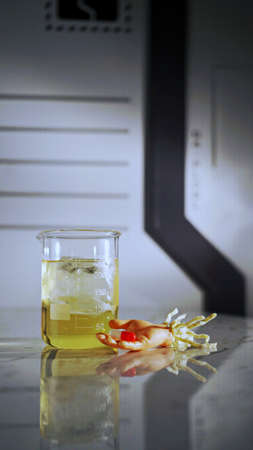 Halloween lab, toy dummy hand holding capsule and graduated glassの写真素材