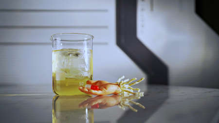 Halloween lab, toy dummy hand holding capsule and graduated glassの写真素材