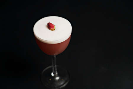 A glass of pink cocktail on a black backgroundの写真素材