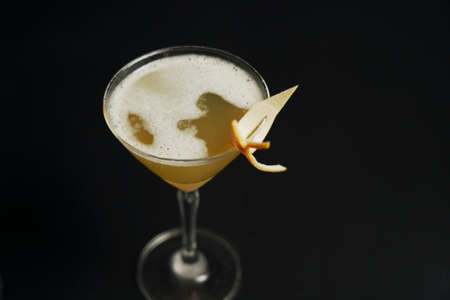 A glass of golden cocktail on a black backgroundの写真素材