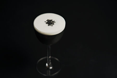 A glass of frothy cocktail on a black backgroundの写真素材