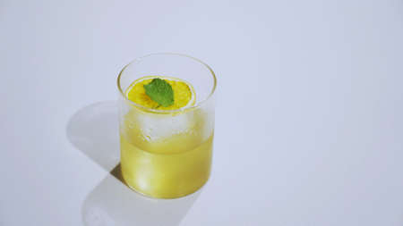 A glass of yellow fruit drink in front of white backgroundの写真素材