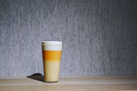 A glass of frothy drink layered in three colors on a wooden countertopの写真素材