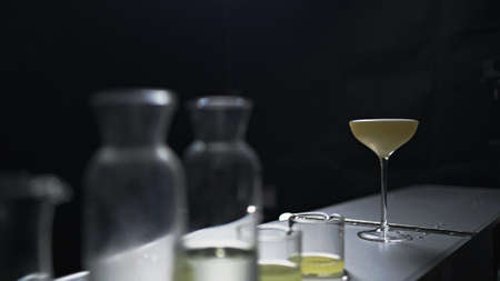 A cocktail stands behind many glass bottlesの写真素材