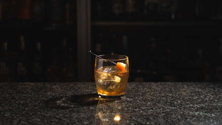 A glass of old fashioned cocktail on the marble bar