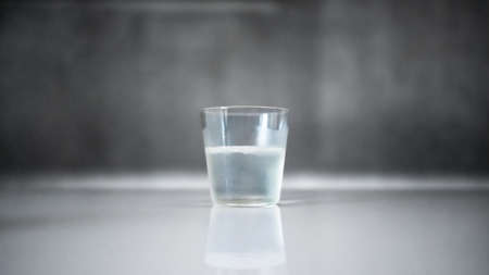 A glass of clear drink on a gray backgroundの写真素材