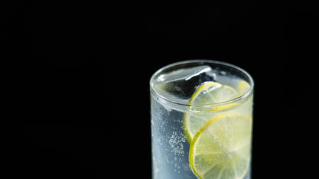A glass of sparkling lime drink on a black backgroundの写真素材