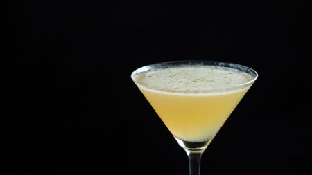 A glass of Whiskey Sour cocktail on a black backgroundの写真素材