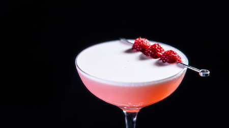 A glass of Clover Club cocktail on a black background