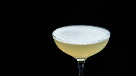 A glass of Bee's Knees cocktail on a black backgroundの写真素材