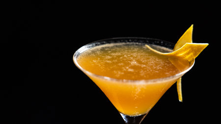 Close up of orange cocktail in martini glass on black background.の写真素材