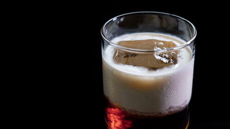 cocktail in a glass with ice cubes on a black backgroundの写真素材