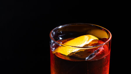 cocktail with orange peel and ice in a glass on a black backgroundの写真素材
