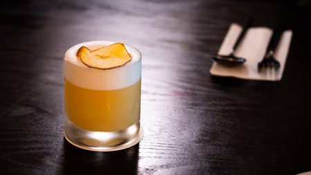 cocktail in a glass on a wooden table with spoon and fork