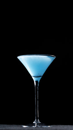 Blue cocktail in martini glass, isolated on black backgroundの写真素材