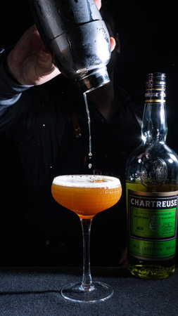 Barman pours a cocktail from a shaker into a glassの写真素材