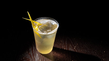 Cocktail with lemon and ice on a wooden table in the dark.の写真素材