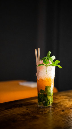 Mojito cocktail with orange, mint and ice on wooden tableの写真素材