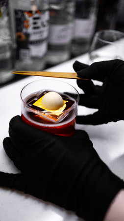 Close-up of female hands in black gloves holding glass of cocktail with iceの写真素材