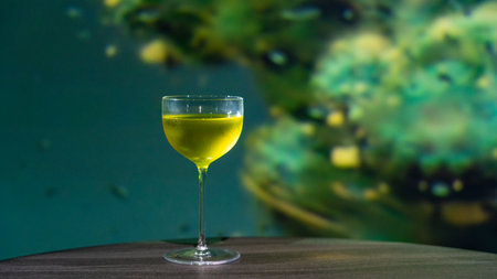 Yellow cocktail in a glass on a wooden table with a blurred backgroundの写真素材