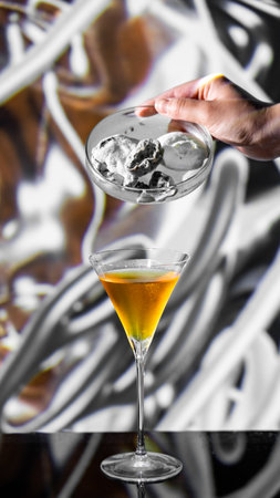 Close-up image of female hand holding martini glass with ice cubeの写真素材