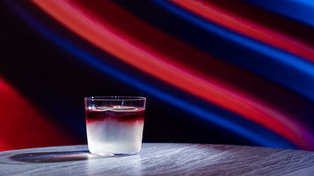 A glass of water on a wooden table against a colorful background.の写真素材