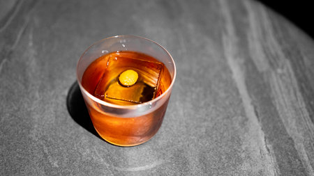 Glass of whiskey with ice cubes on a wooden table, top viewの写真素材