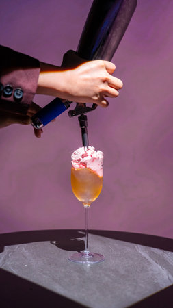 Bartender decorating a cocktail with pink and white whipped creamの写真素材