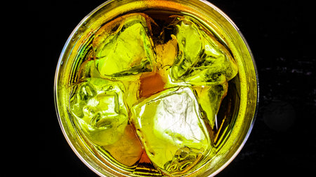 Whiskey with ice cubes in a glass on a black backgroundの写真素材