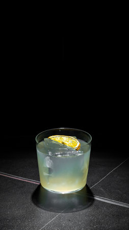 Cocktail with lemon and ice on black background, copy spaceの写真素材