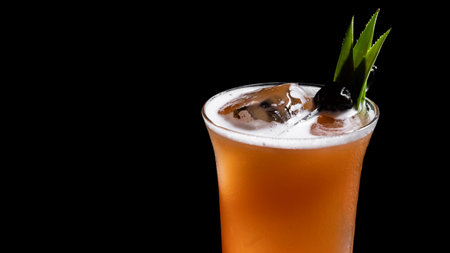 Cocktail on a black background with ice cubes and a green leafの写真素材