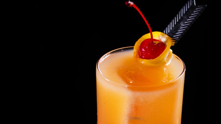 A glass of classic Tequila Sunrise cocktail on a black backgroundの写真素材