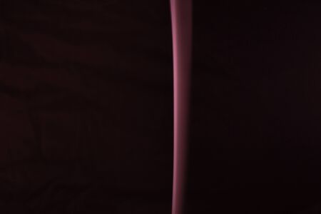 A thin red streak of smoke flowing top on a dark backgroundの写真素材