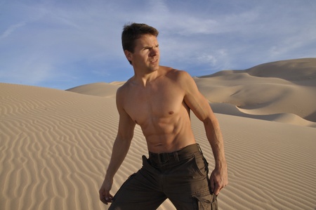Sexy muscular man hiking in desert sand dunesの写真素材